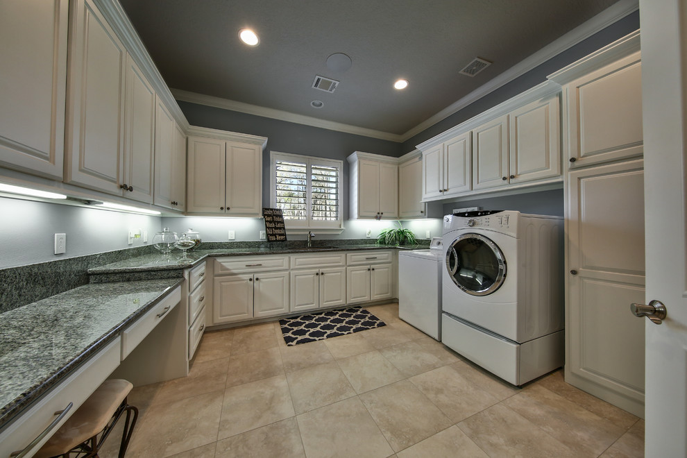Inspiration for a large transitional u-shaped travertine floor and beige floor utility room remodel in Houston with an undermount sink, beaded inset cabinets, white cabinets, granite countertops, gray walls and a side-by-side washer/dryer