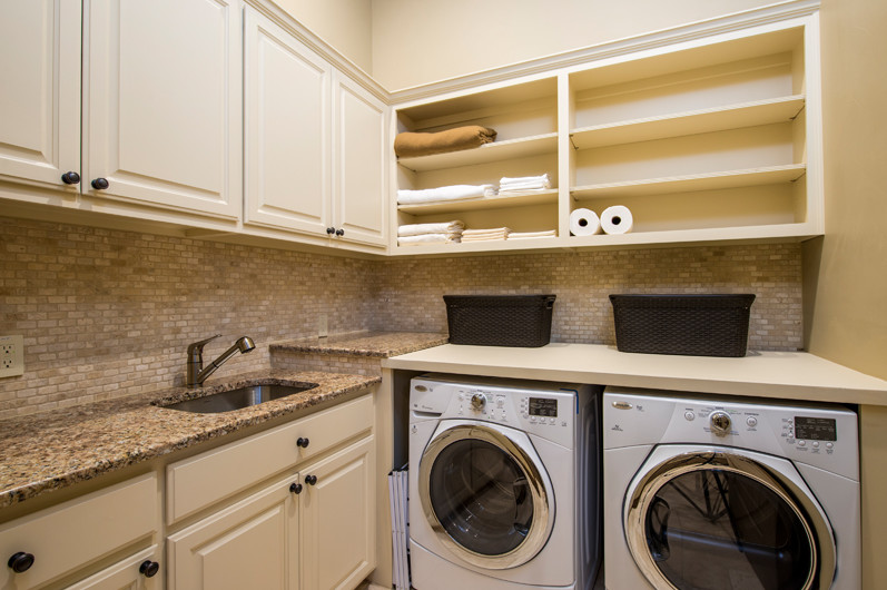 Inspiration for a mid-sized transitional l-shaped utility room remodel in Austin with a single-bowl sink, shaker cabinets, beige cabinets, granite countertops, beige walls and a side-by-side washer/dryer