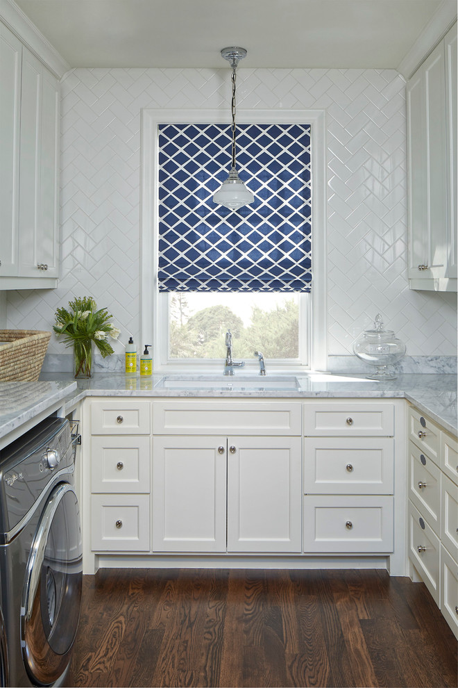 Photo of a large classic u-shaped separated utility room in Dallas with shaker cabinets, white cabinets, marble worktops, white splashback, ceramic splashback, medium hardwood flooring, a submerged sink, white walls and a side by side washer and dryer.