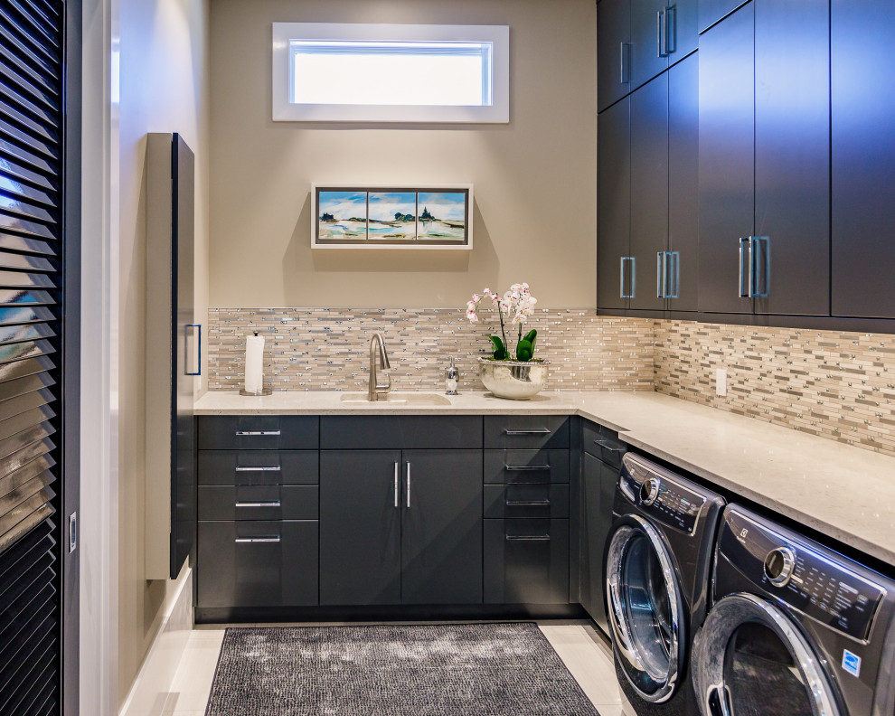 Contemporary l-shaped utility room in Tampa with a submerged sink, flat-panel cabinets, grey cabinets, beige walls, a side by side washer and dryer, white floors and beige worktops.