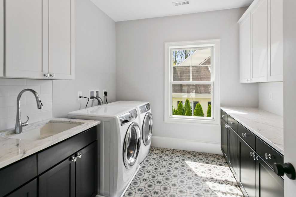 Foto på en mellanstor funkis flerfärgade parallell tvättstuga enbart för tvätt, med en undermonterad diskho, skåp i shakerstil, svarta skåp, grå väggar, en tvättmaskin och torktumlare bredvid varandra och flerfärgat golv
