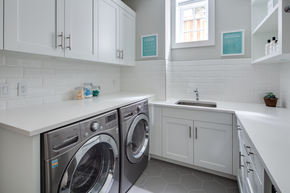 Photo of a medium sized classic u-shaped separated utility room in Vancouver with a submerged sink, shaker cabinets, white cabinets, engineered stone countertops, grey walls, porcelain flooring, a side by side washer and dryer, grey floors and white worktops.