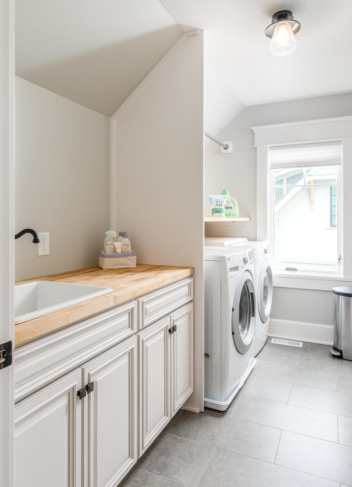 Dedicated laundry room - mid-sized craftsman single-wall porcelain tile dedicated laundry room idea in Nashville with a drop-in sink, raised-panel cabinets, white cabinets, wood countertops, gray walls, a side-by-side washer/dryer and beige countertops