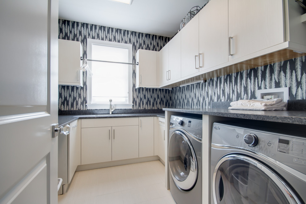 Exempel på en mellanstor modern tvättstuga enbart för tvätt, med en undermonterad diskho, släta luckor, vita skåp, flerfärgade väggar, en tvättmaskin och torktumlare bredvid varandra och laminatbänkskiva