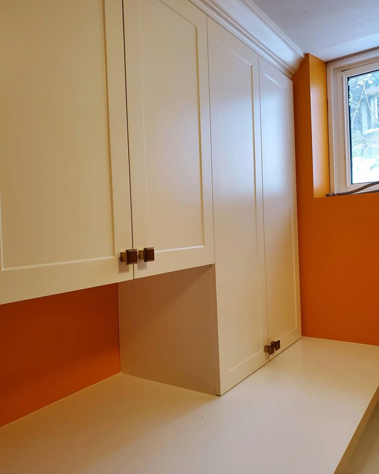 Свежая идея для дизайна: прямая прачечная с фасадами в стиле шейкер, белыми фасадами, оранжевыми стенами, со стиральной и сушильной машиной рядом и белой столешницей - отличное фото интерьера