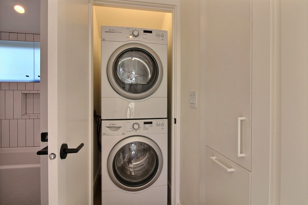 Esempio di un piccolo ripostiglio-lavanderia minimalista con pareti bianche e lavatrice e asciugatrice a colonna