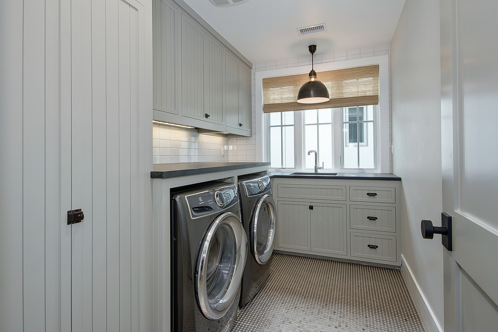 Photo of a medium sized rural l-shaped separated utility room in Orange County with a submerged sink, recessed-panel cabinets, grey cabinets, soapstone worktops, grey walls, a side by side washer and dryer and black worktops.