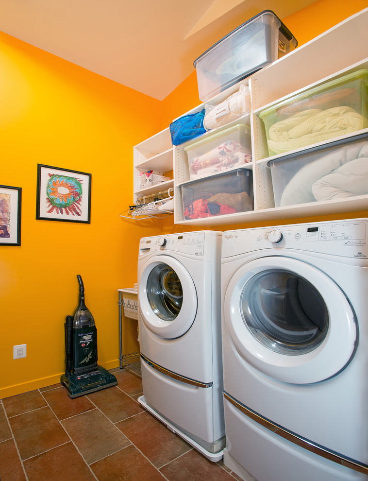 Photo of a traditional utility room in DC Metro with an utility sink, a side by side washer and dryer and orange walls.