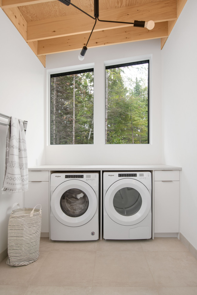 This is an example of a scandi utility room in Other with flat-panel cabinets, white cabinets, ceramic flooring and a side by side washer and dryer.