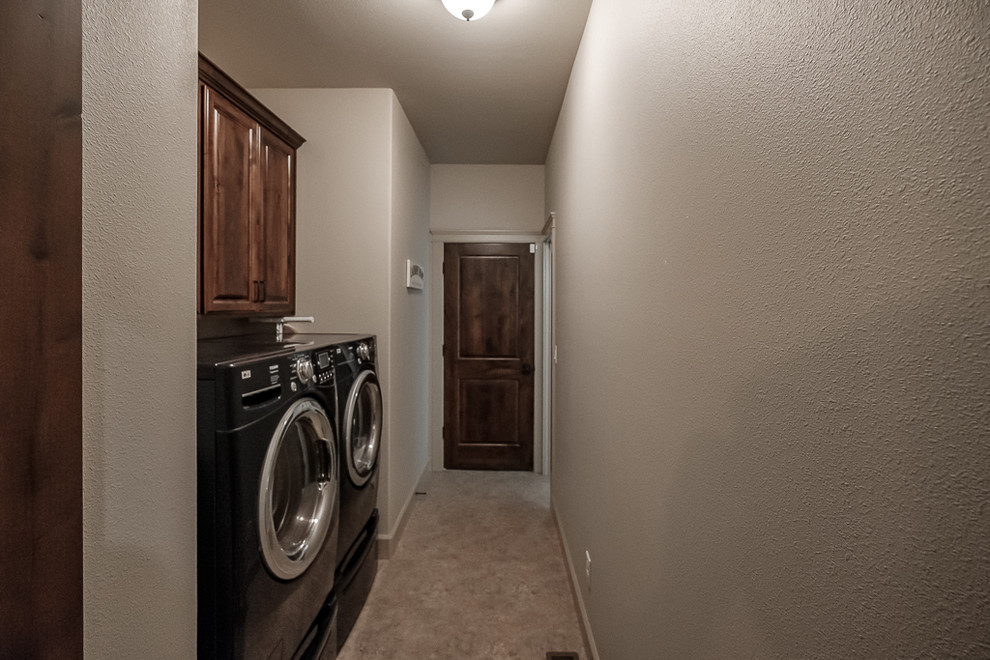 Immagine di una lavanderia chic con ante con bugna sagomata, ante in legno bruno, pareti beige, moquette, lavatrice e asciugatrice affiancate e pavimento beige