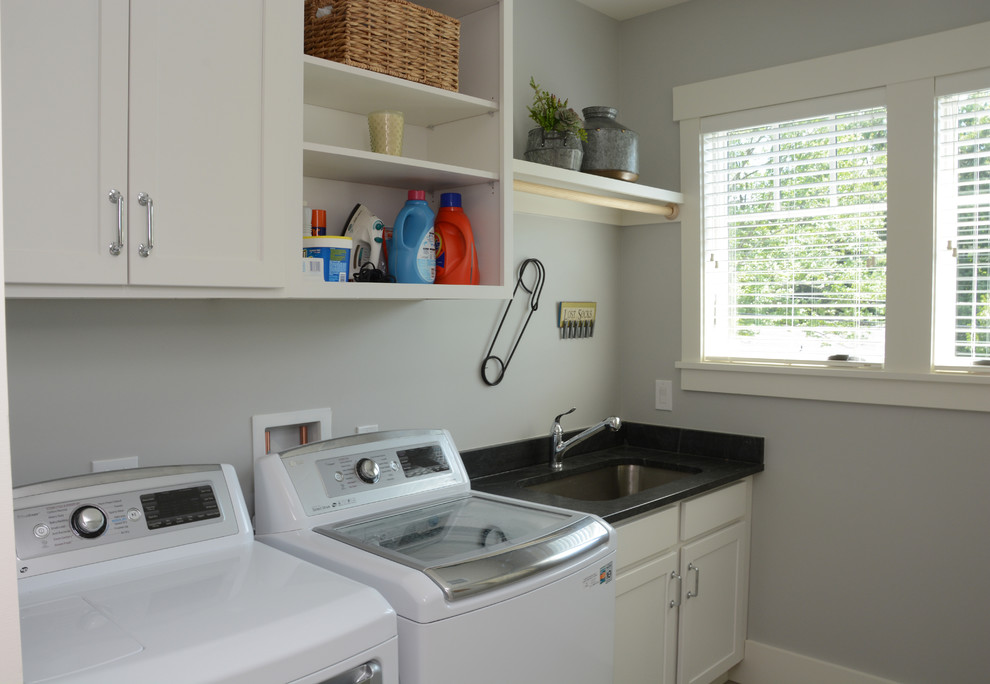 Idee per un piccolo ripostiglio-lavanderia chic con lavello a vasca singola, ante con riquadro incassato, ante bianche, pareti grigie e lavatrice e asciugatrice affiancate