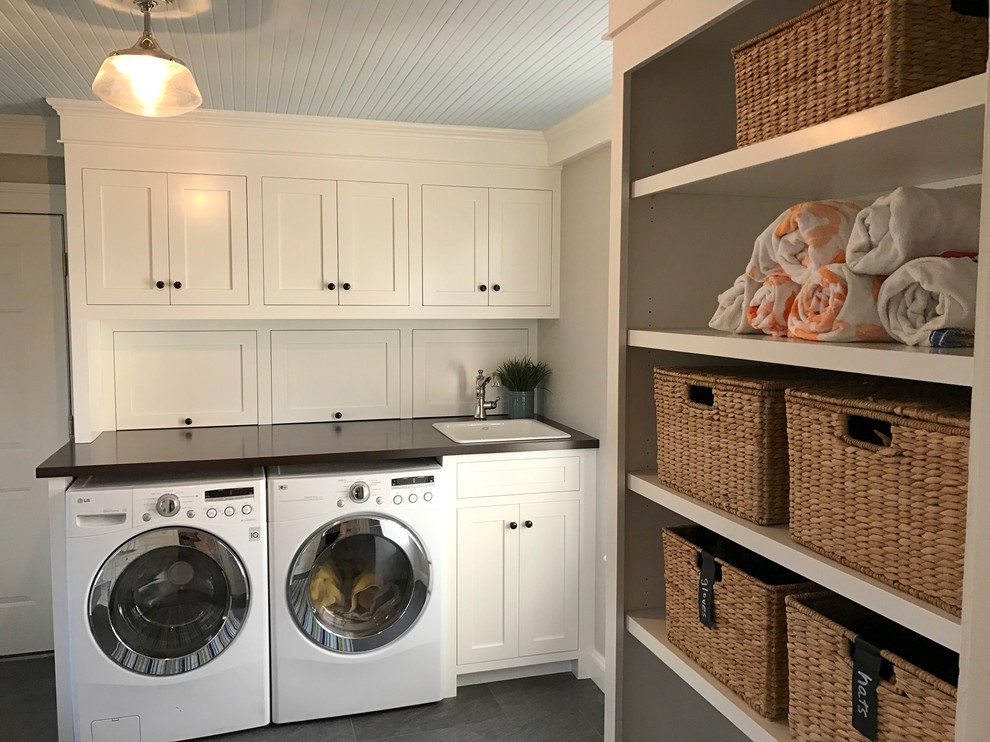 Photo of a medium sized classic u-shaped utility room in New York with a built-in sink, beaded cabinets, white cabinets, wood worktops, grey walls, porcelain flooring and a side by side washer and dryer.