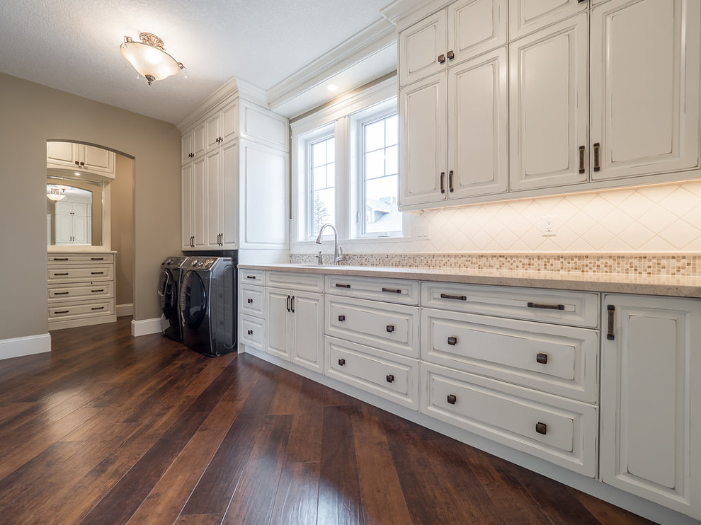 Inspiration for a large classic l-shaped separated utility room in Edmonton with a built-in sink, raised-panel cabinets, white cabinets, granite worktops, beige walls, vinyl flooring, a side by side washer and dryer and multi-coloured floors.