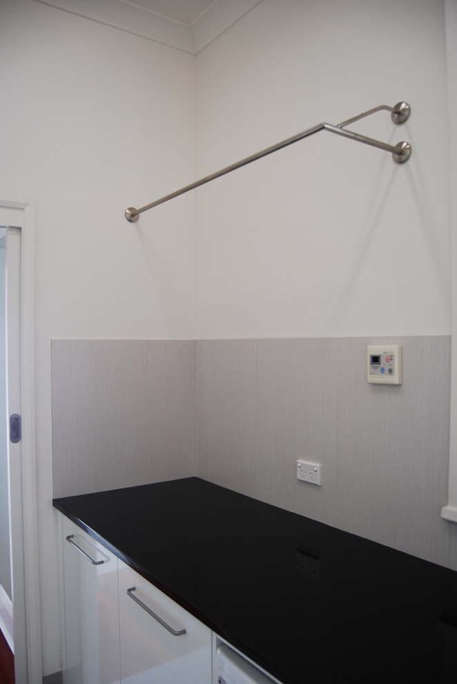 Large contemporary galley separated utility room in Sydney with a submerged sink, flat-panel cabinets, white cabinets, granite worktops, white walls, ceramic flooring and a side by side washer and dryer.