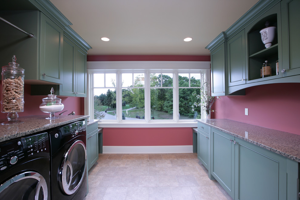 Klassisk inredning av ett stort parallellt grovkök, med luckor med infälld panel, gröna skåp, granitbänkskiva, röda väggar, skiffergolv och en tvättmaskin och torktumlare bredvid varandra