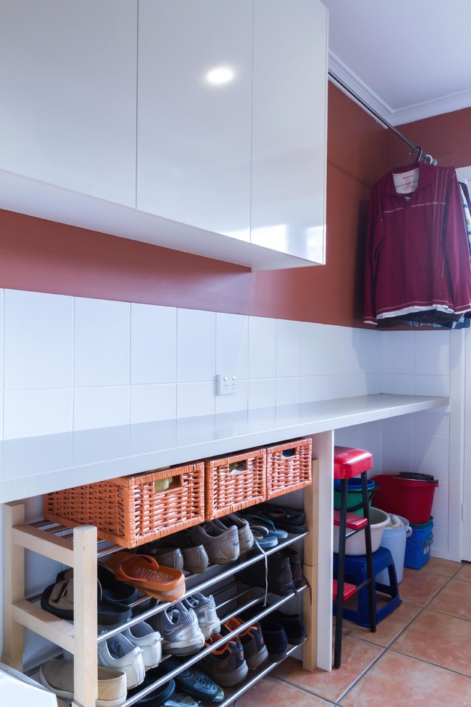 Esempio di una piccola lavanderia multiuso moderna con ante lisce, ante bianche, top in quarzo composito, pavimento con piastrelle in ceramica e pavimento arancione