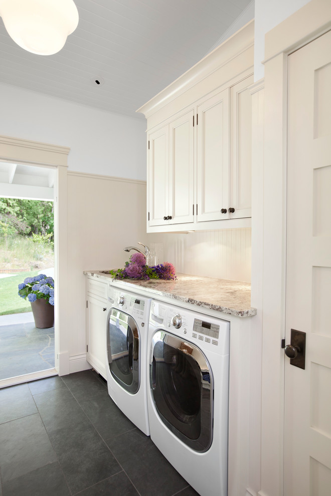 Foto di una lavanderia tradizionale con ante con riquadro incassato, ante beige, lavatrice e asciugatrice affiancate, pavimento nero e top beige