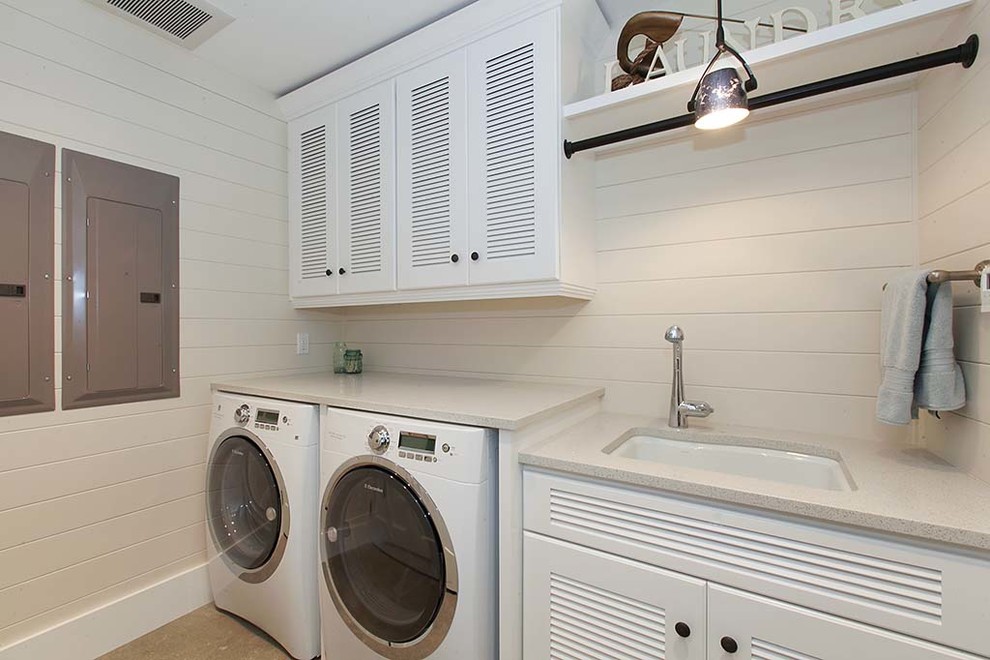 シアトルにある中くらいなビーチスタイルのおしゃれな洗濯室 (I型、アンダーカウンターシンク、ルーバー扉のキャビネット、白いキャビネット、クオーツストーンカウンター、ベージュの壁、セラミックタイルの床、左右配置の洗濯機・乾燥機) の写真