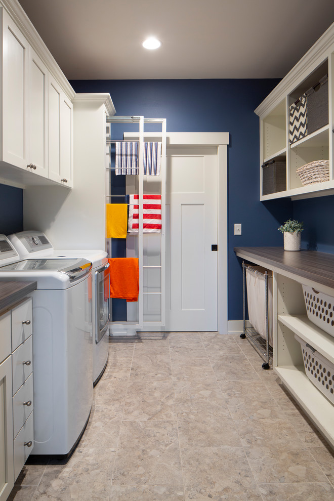 ミルウォーキーにある中くらいなトラディショナルスタイルのおしゃれな家事室 (ll型、フラットパネル扉のキャビネット、白いキャビネット、ラミネートカウンター、青い壁、左右配置の洗濯機・乾燥機、グレーのキッチンカウンター、スロップシンク) の写真