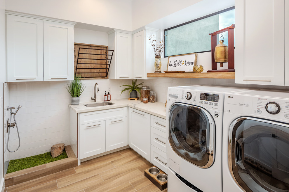 Example of a transitional l-shaped beige floor utility room design in Phoenix with an undermount sink, shaker cabinets, white cabinets, white walls, a side-by-side washer/dryer and white countertops