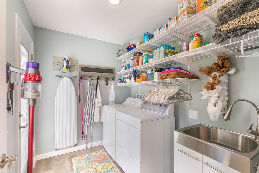 Idee per una piccola sala lavanderia eclettica con ante lisce, ante bianche, pareti blu, pavimento con piastrelle in ceramica, lavatrice e asciugatrice affiancate e pavimento beige