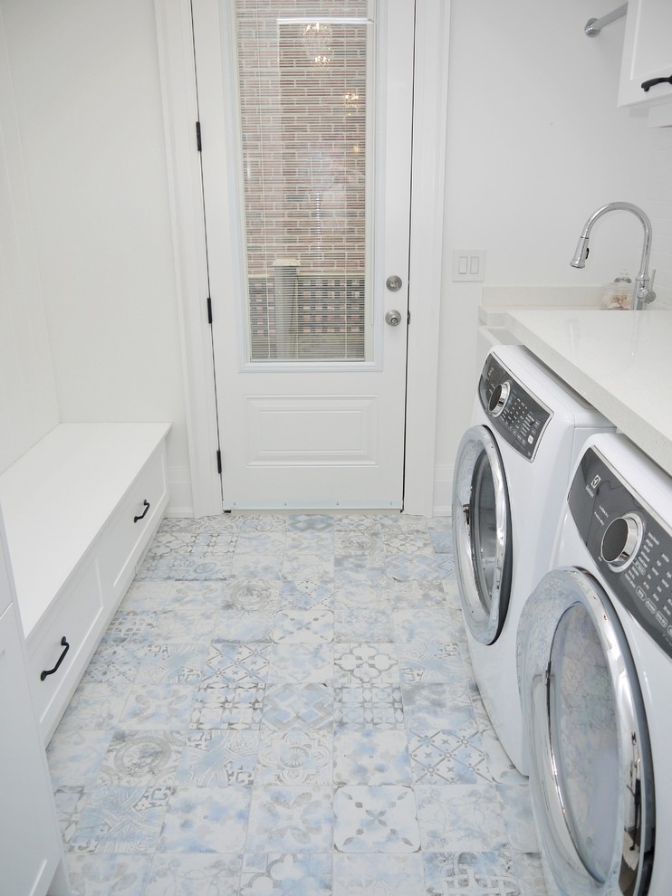 Inspiration for a medium sized traditional galley utility room in Toronto with a belfast sink, shaker cabinets, white cabinets, engineered stone countertops, white walls, porcelain flooring, a side by side washer and dryer, blue floors and white worktops.
