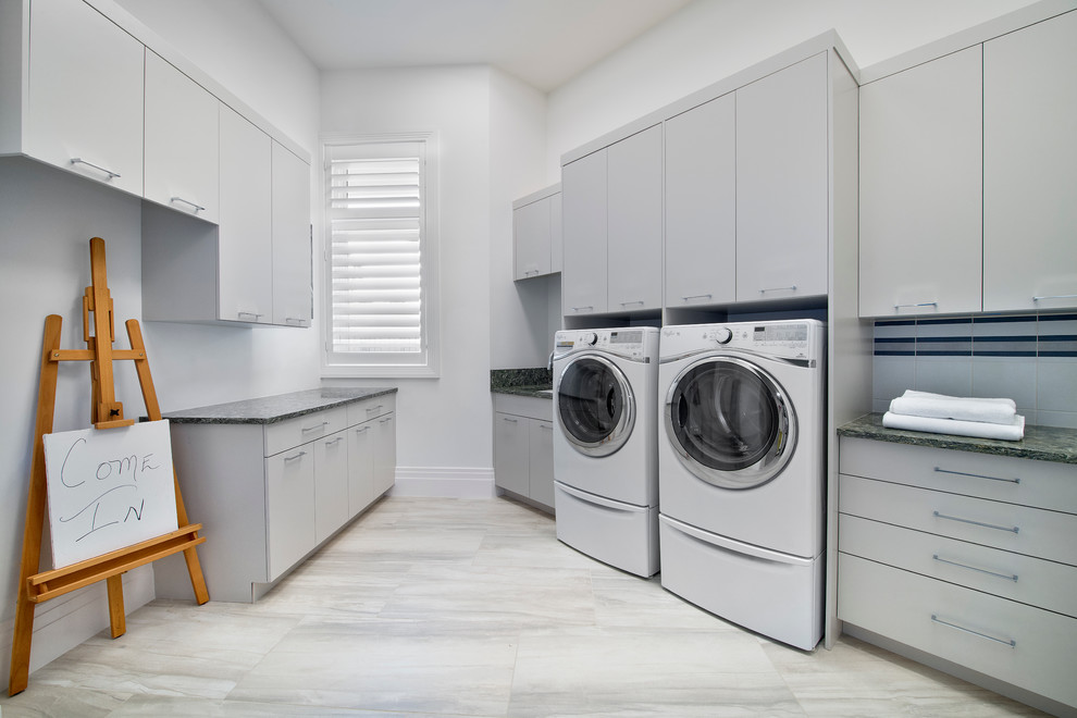 マイアミにある広いコンテンポラリースタイルのおしゃれな洗濯室 (コの字型、アンダーカウンターシンク、フラットパネル扉のキャビネット、グレーのキャビネット、グレーの壁、左右配置の洗濯機・乾燥機) の写真