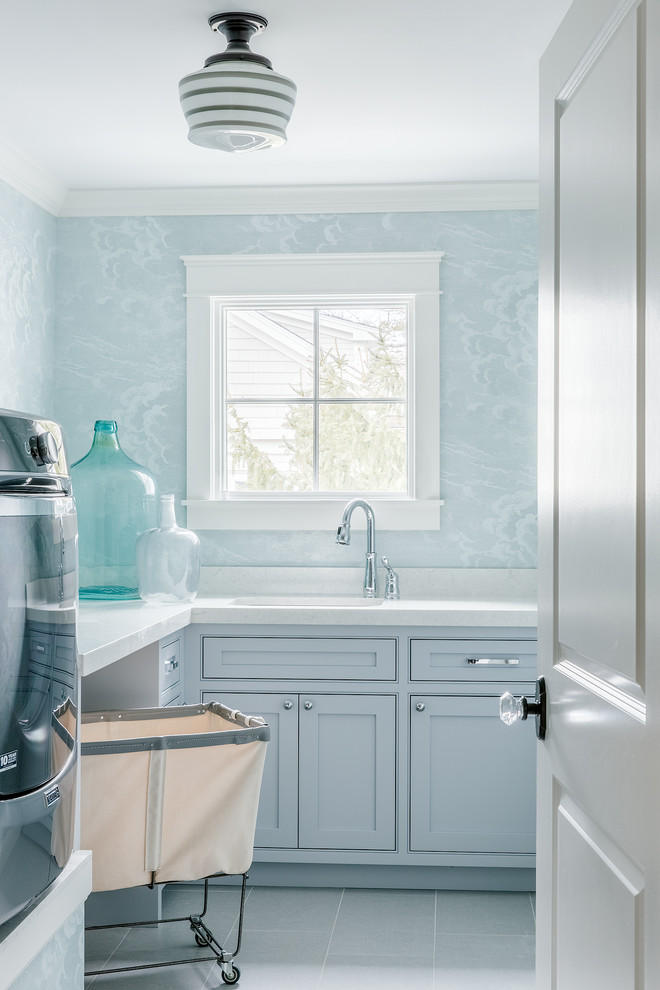 Bild på en lantlig tvättstuga enbart för tvätt, med en undermonterad diskho, bänkskiva i kvarts, klinkergolv i keramik, en tvättmaskin och torktumlare bredvid varandra och blå väggar