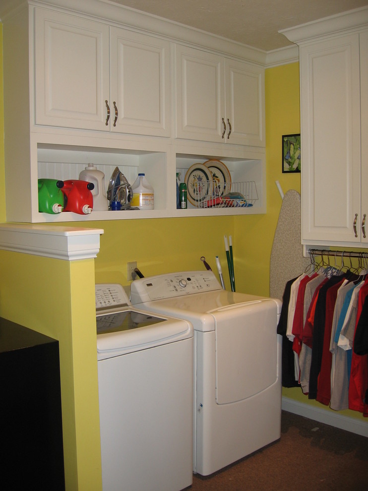 Inspiration för ett mellanstort vintage l-format grovkök, med luckor med upphöjd panel, vita skåp, gula väggar, heltäckningsmatta och en tvättmaskin och torktumlare bredvid varandra