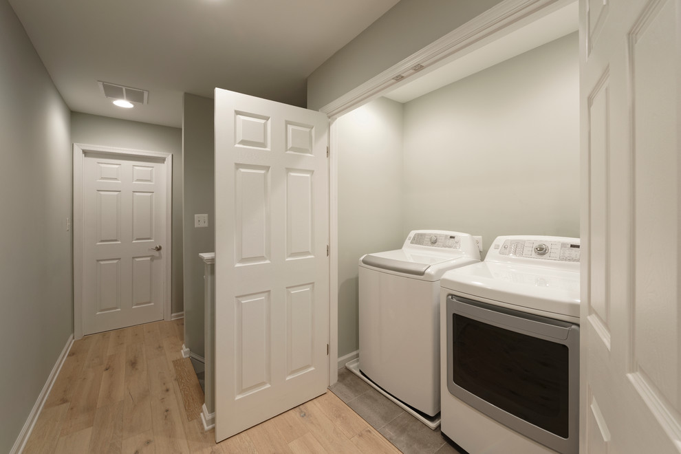 Imagen de armario lavadero lineal clásico pequeño con paredes grises, suelo de baldosas de cerámica y lavadora y secadora juntas