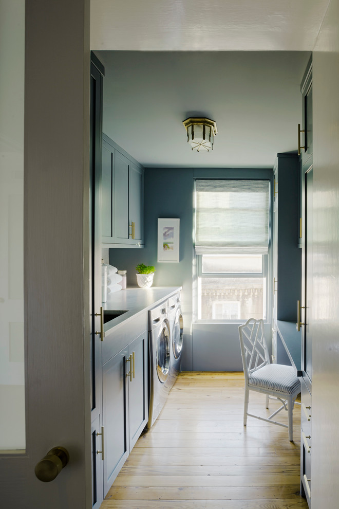 Exempel på ett litet modernt parallellt grovkök, med en undermonterad diskho, skåp i shakerstil, blå skåp, marmorbänkskiva, ljust trägolv, en tvättmaskin och torktumlare bredvid varandra och grå väggar