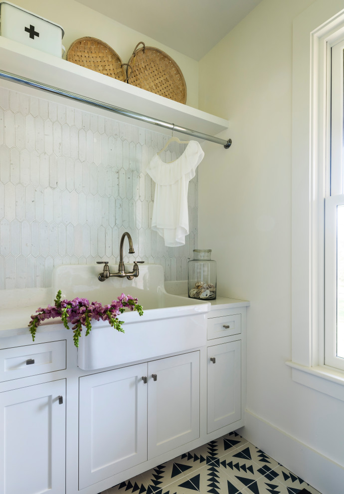 Immagine di una lavanderia stile marino con lavello stile country, ante in stile shaker, ante bianche, pareti bianche, pavimento multicolore e top bianco