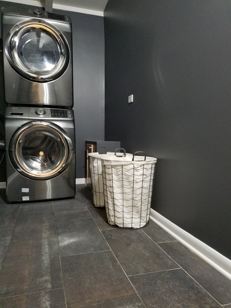 シカゴにある中くらいなコンテンポラリースタイルのおしゃれな洗濯室 (黒い壁、クッションフロア、上下配置の洗濯機・乾燥機、茶色い床) の写真