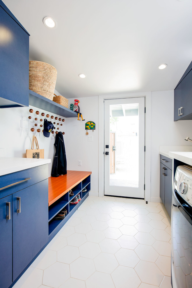 ロサンゼルスにあるミッドセンチュリースタイルのおしゃれな家事室 (ll型、フラットパネル扉のキャビネット、青いキャビネット、白い壁、左右配置の洗濯機・乾燥機、ベージュの床、白いキッチンカウンター) の写真