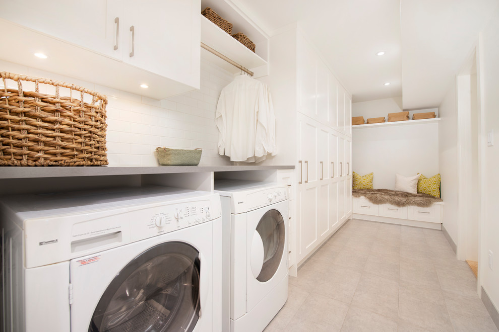 Mid-sized transitional l-shaped gray floor and porcelain tile dedicated laundry room photo in Vancouver with shaker cabinets, white cabinets, white walls, a side-by-side washer/dryer, quartz countertops and gray countertops