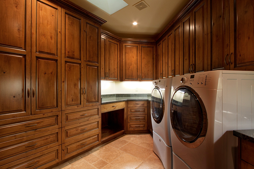 Example of a large classic galley travertine floor utility room design in Other with raised-panel cabinets, medium tone wood cabinets, granite countertops, white walls and a side-by-side washer/dryer