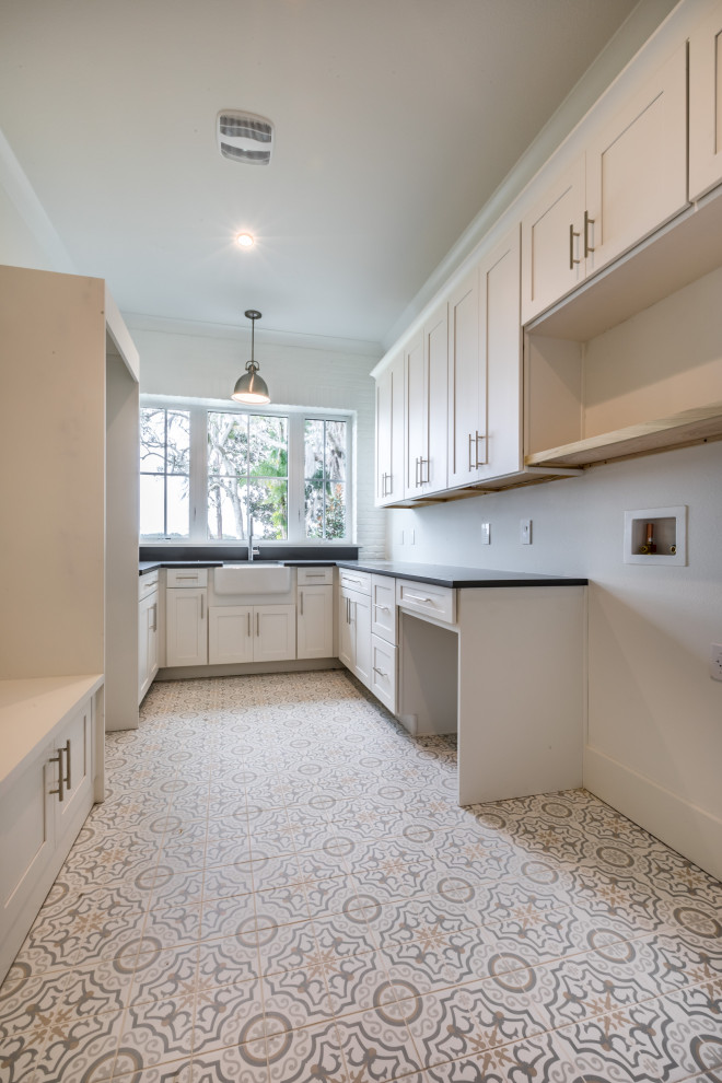 Design ideas for a medium sized country galley separated utility room in Orlando with a belfast sink, shaker cabinets, white cabinets, engineered stone countertops, white walls, ceramic flooring, a side by side washer and dryer, white floors and black worktops.