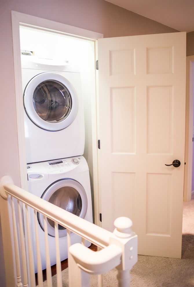 Immagine di un piccolo ripostiglio-lavanderia tradizionale con lavatrice e asciugatrice a colonna, pareti beige e moquette