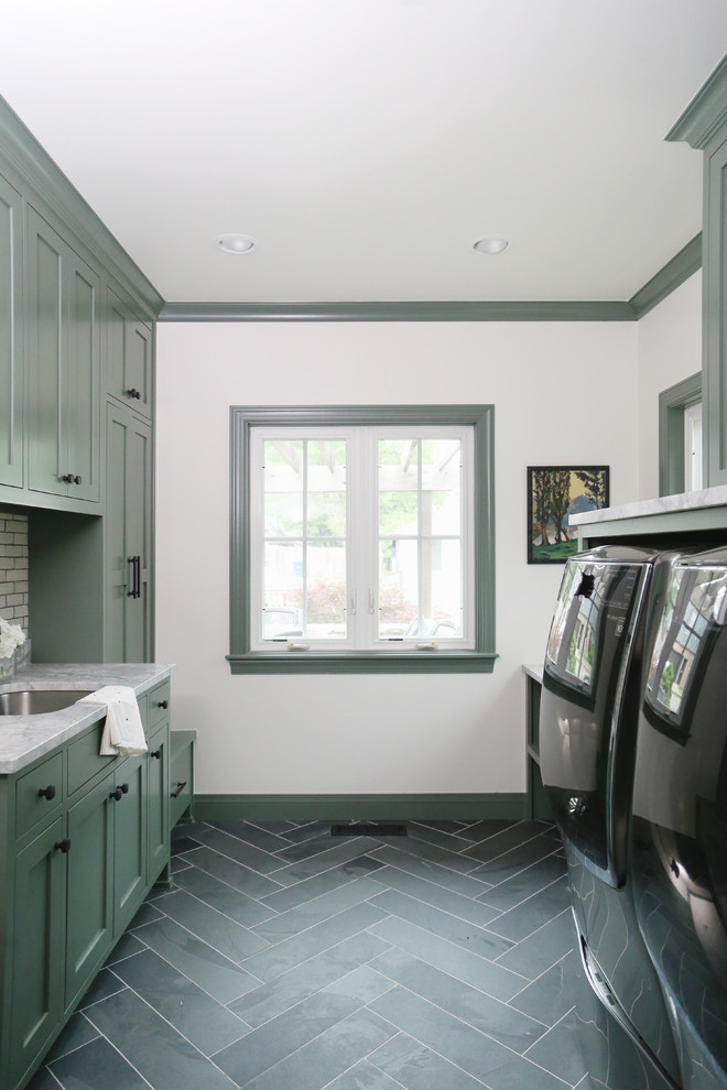 Klassisk inredning av ett mellanstort grå parallellt grått grovkök, med en undermonterad diskho, skåp i shakerstil, gröna skåp, marmorbänkskiva, vita väggar, en tvättmaskin och torktumlare bredvid varandra, vinylgolv och grått golv