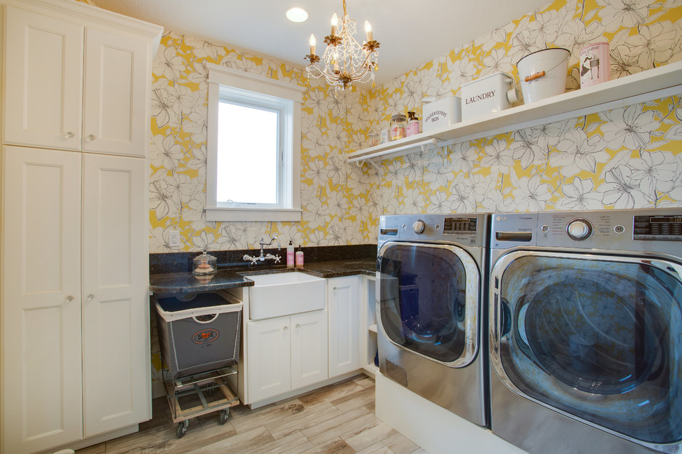 Modelo de cuarto de lavado tradicional con fregadero sobremueble, armarios estilo shaker, puertas de armario blancas, encimera de granito, paredes amarillas, lavadora y secadora juntas y suelo marrón