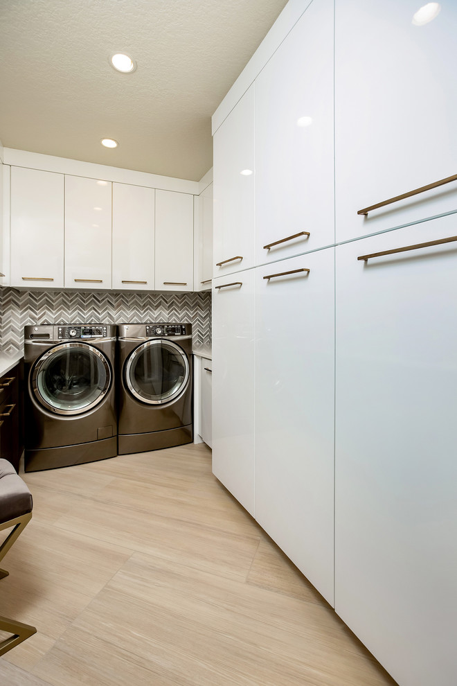 Idéer för en stor modern vita u-formad tvättstuga enbart för tvätt, med släta luckor, vita skåp, bänkskiva i kvarts, flerfärgade väggar, ljust trägolv, en tvättmaskin och torktumlare bredvid varandra och beiget golv