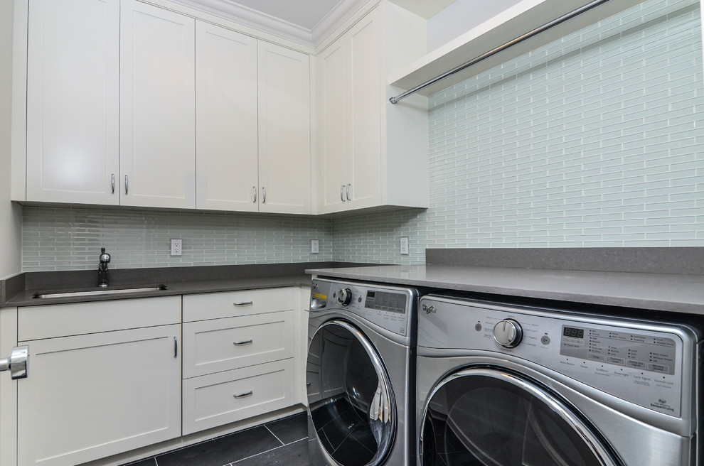 This is an example of a medium sized l-shaped separated utility room in New York with a submerged sink, shaker cabinets, white cabinets, engineered stone countertops, white walls, slate flooring, a side by side washer and dryer and black floors.