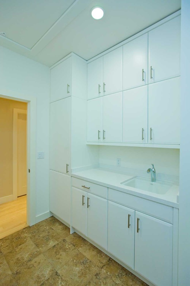 Inspiration for a large contemporary u-shaped separated utility room in San Francisco with a submerged sink, flat-panel cabinets, white cabinets, composite countertops, white walls, ceramic flooring and a side by side washer and dryer.
