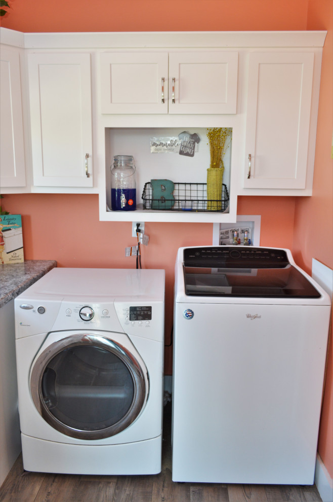 Exempel på en mellanstor lantlig grå l-formad grått tvättstuga enbart för tvätt, med en nedsänkt diskho, skåp i shakerstil, vita skåp, laminatbänkskiva, rosa väggar, laminatgolv, en tvättmaskin och torktumlare bredvid varandra och brunt golv