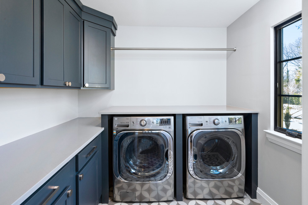 Immagine di una sala lavanderia moderna di medie dimensioni con ante in stile shaker, ante blu, top in quarzo composito, pareti grigie, lavatrice e asciugatrice affiancate, pavimento grigio e top grigio