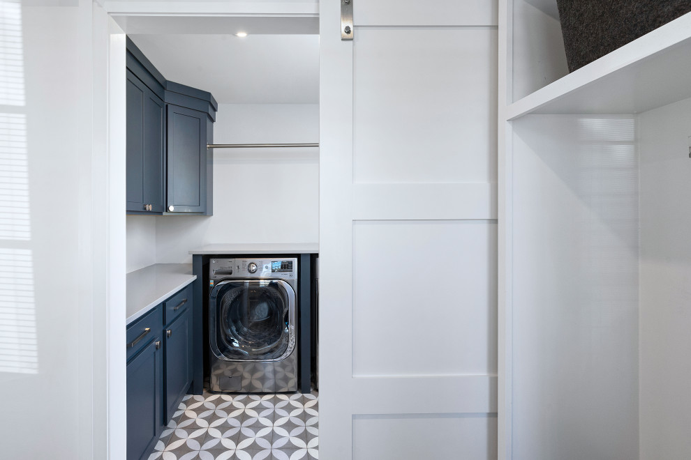 Inspiration for a mid-sized modern gray floor dedicated laundry room remodel with shaker cabinets, blue cabinets, quartz countertops, gray walls, a side-by-side washer/dryer and gray countertops