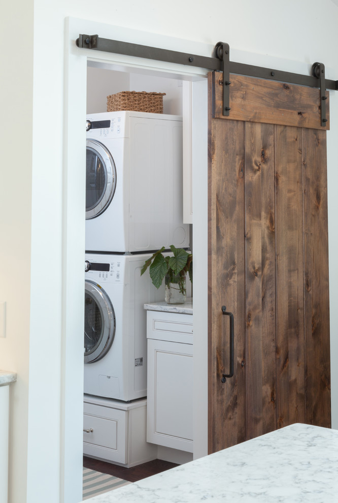 Modelo de cuarto de lavado lineal clásico renovado de tamaño medio con armarios con rebordes decorativos, puertas de armario blancas y encimera de mármol
