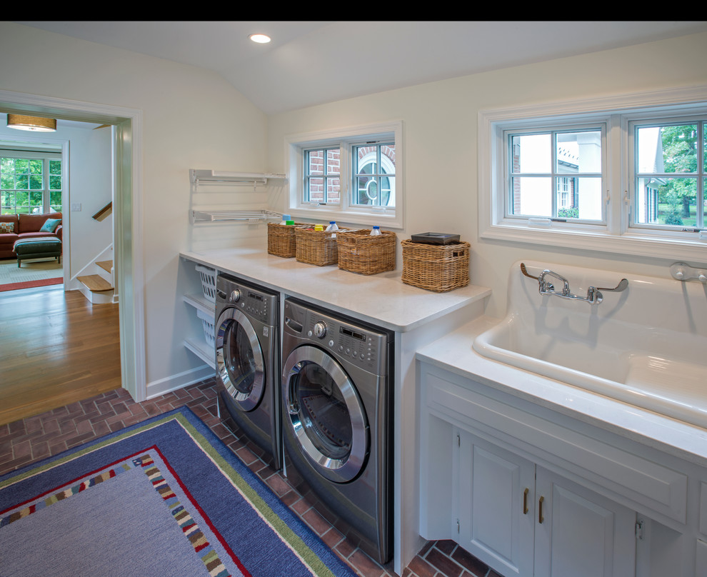 Immagine di una sala lavanderia classica con lavello da incasso, ante con riquadro incassato, ante bianche, top in laminato, pareti bianche, pavimento in vinile e lavatrice e asciugatrice affiancate