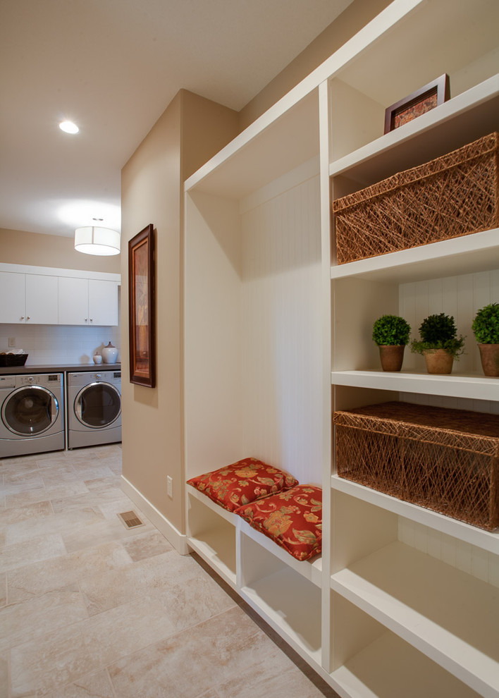 Classic utility room in Vancouver with flat-panel cabinets, white cabinets, a side by side washer and dryer and beige floors.