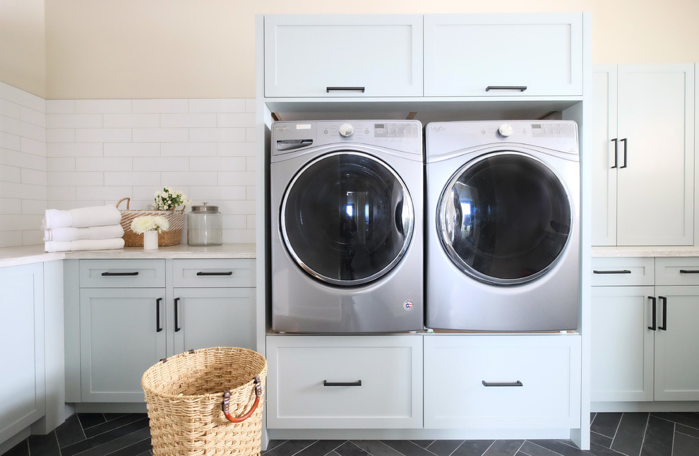 Einzeilige, Mittelgroße Landhausstil Waschküche mit Schrankfronten im Shaker-Stil, weißen Schränken, Waschmaschine und Trockner nebeneinander, grauem Boden und beiger Arbeitsplatte